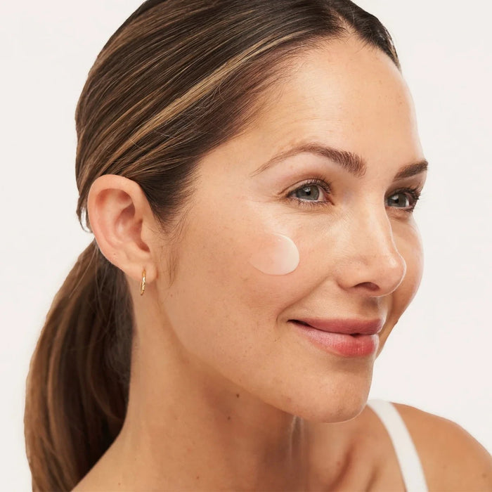 Shop Rescue Spa C-RADICAL Defense antioxidant serum applied as a small dot on a woman's cheek for skin brightening