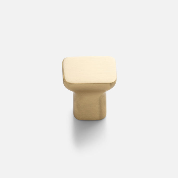 Close-up view of Cascade Knob showcasing its sloping organic silhouette in natural brass on a light background