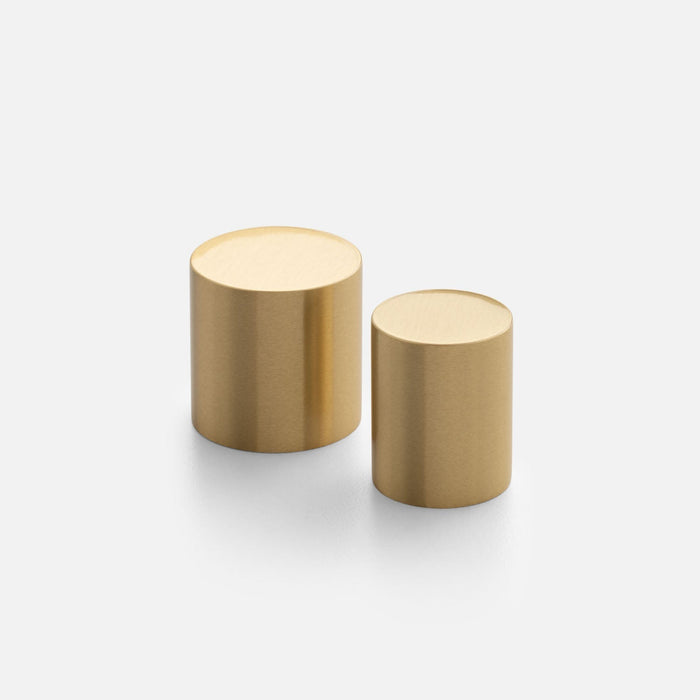 Angled view of two Cove Knobs showcasing cylindrical gold finishes on a white background