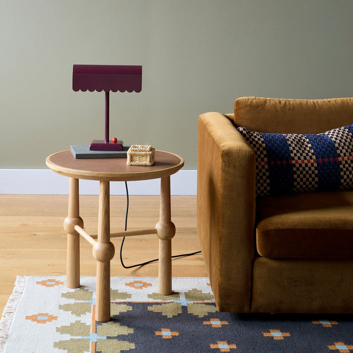 Front view of Dolores Table Lamp showcasing its scalloped edge and contrasting dimmer knob in a living room