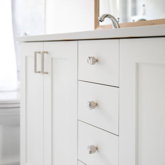 View of Edgecliff Pulls installed on white bathroom vanity drawers with faceted cylindrical fronts