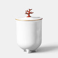 L'Objet footed white porcelain candle with a red coral lid and 24K gold rim accents.