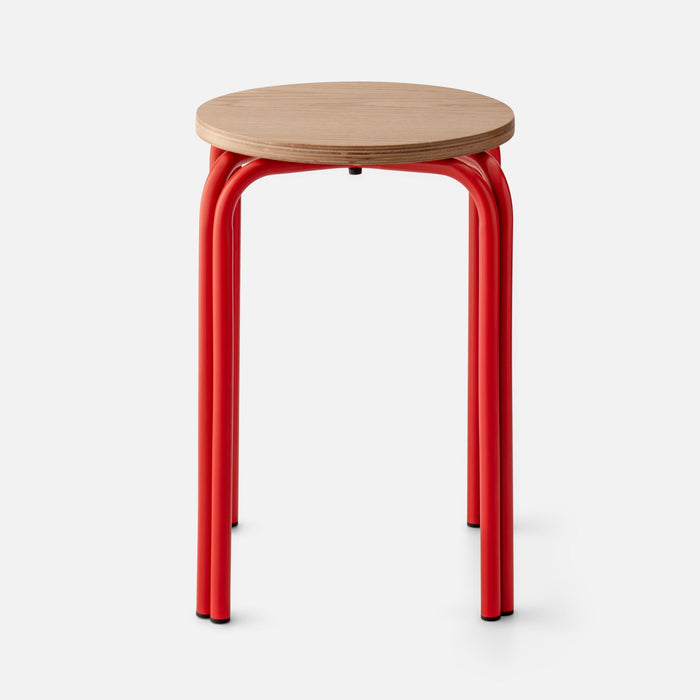 Close-up of Forma Stool showing white oak top with plywood edge and red powder-coated steel legs on white background