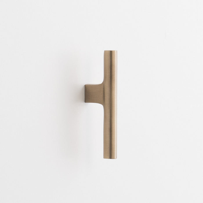 Front view of Galley Pull showcasing asymmetrical intersecting curves in natural brass on a white background