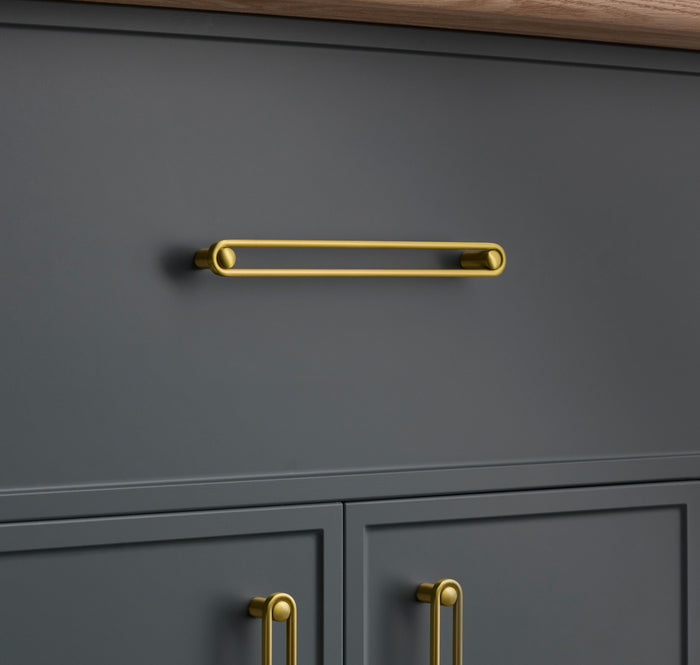 Front view of Landon Pull showcasing its slim gold-tone bar on a dark gray cabinet