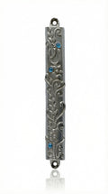 High-resolution image of an Ofir Mezuzah made of pewter, standing 7 inches tall, with intricate engraved Hebrew letters and decorative motifs, on a white studio background with soft reflection.