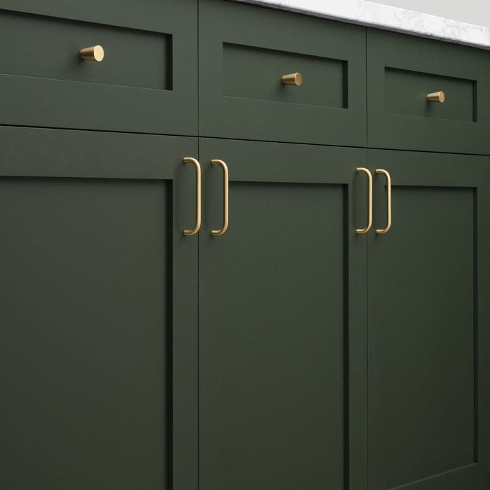 Close-up of Parker Pull hardware installed on dark green cabinetry, showing vertical bar pulls and matching round knobs