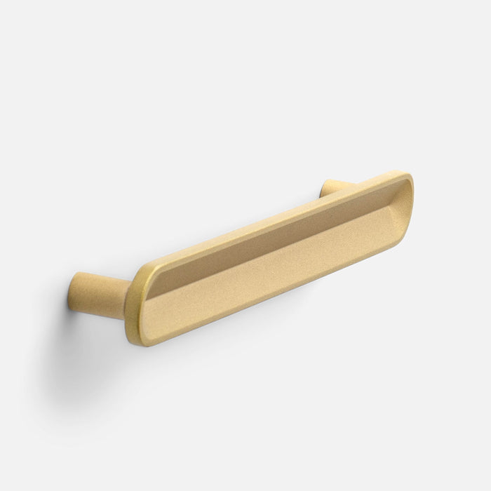 Angled view of Rhone Pull showcasing an elongated recessed grip in cast brass finish against a white background
